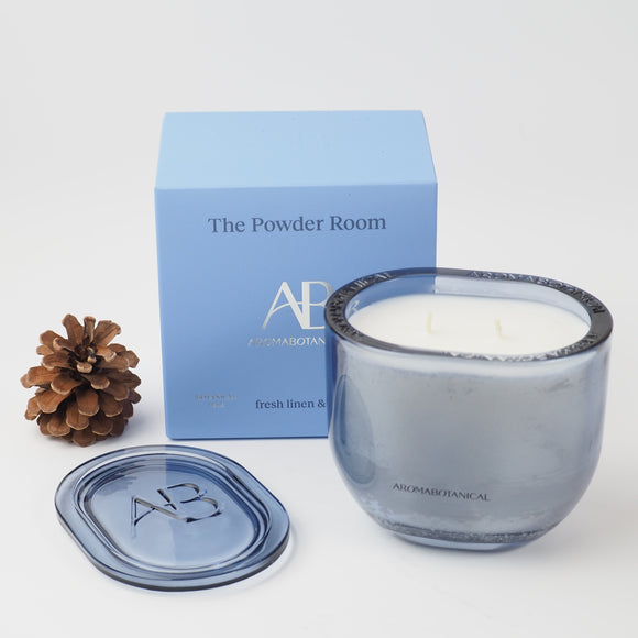 Aromabotanical - the Powder Room luxury scented candle in an elegant smoky blue glass vessel with matching lid. Featuring a soft fresh linen and lily fragrance 400g