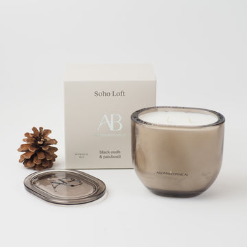Aromabotanical - Soho Loft luxury scented candle in an elegant smoky grey glass vessel with matching lid. Featuring a rich black oudh and patchouli fragrance 400g